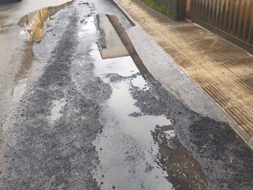Massa asfáltica e emulsão removidas pela chuva em rua movimentada de Marechal Flor