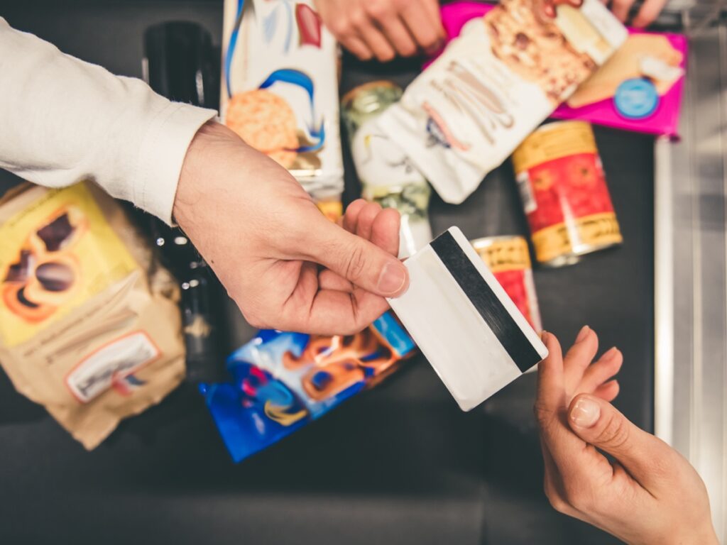 Close-up of man giving a credit card at the cash desk in supermarket
