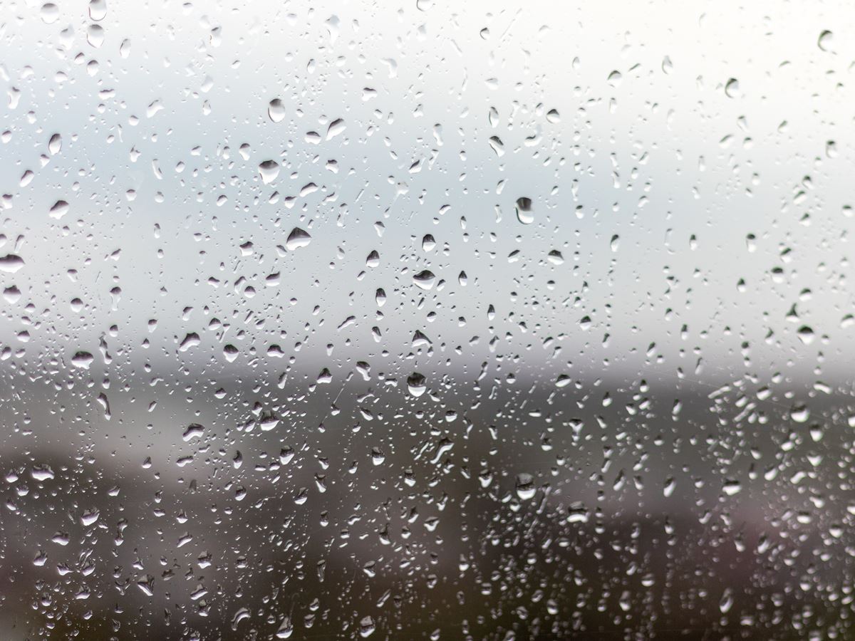 A closeup shot of a window on a rainy day, raindrops rolling down the window