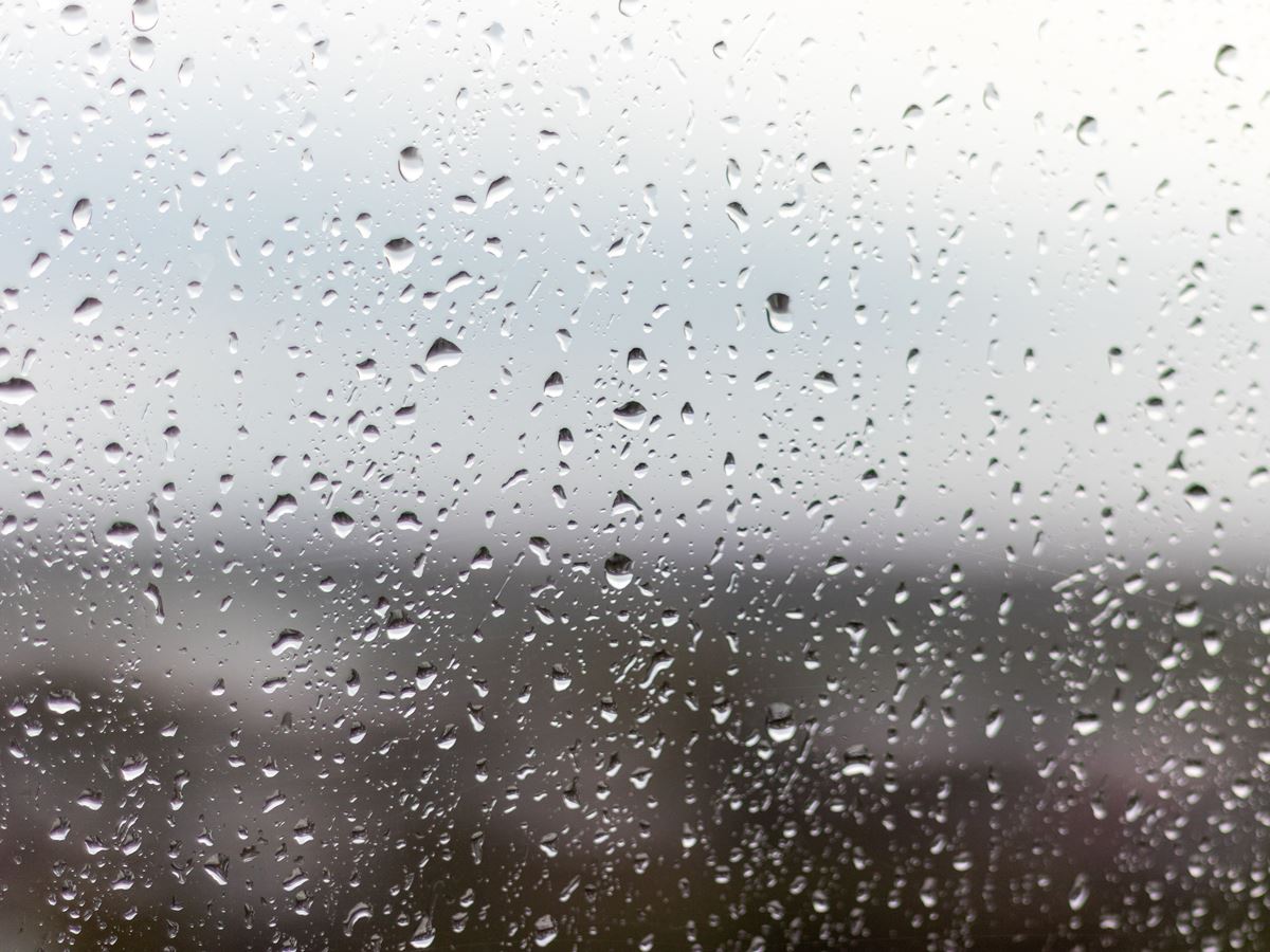 A closeup shot of a window on a rainy day, raindrops rolling down the window