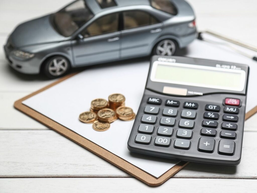 car model,calculator and coins on white table