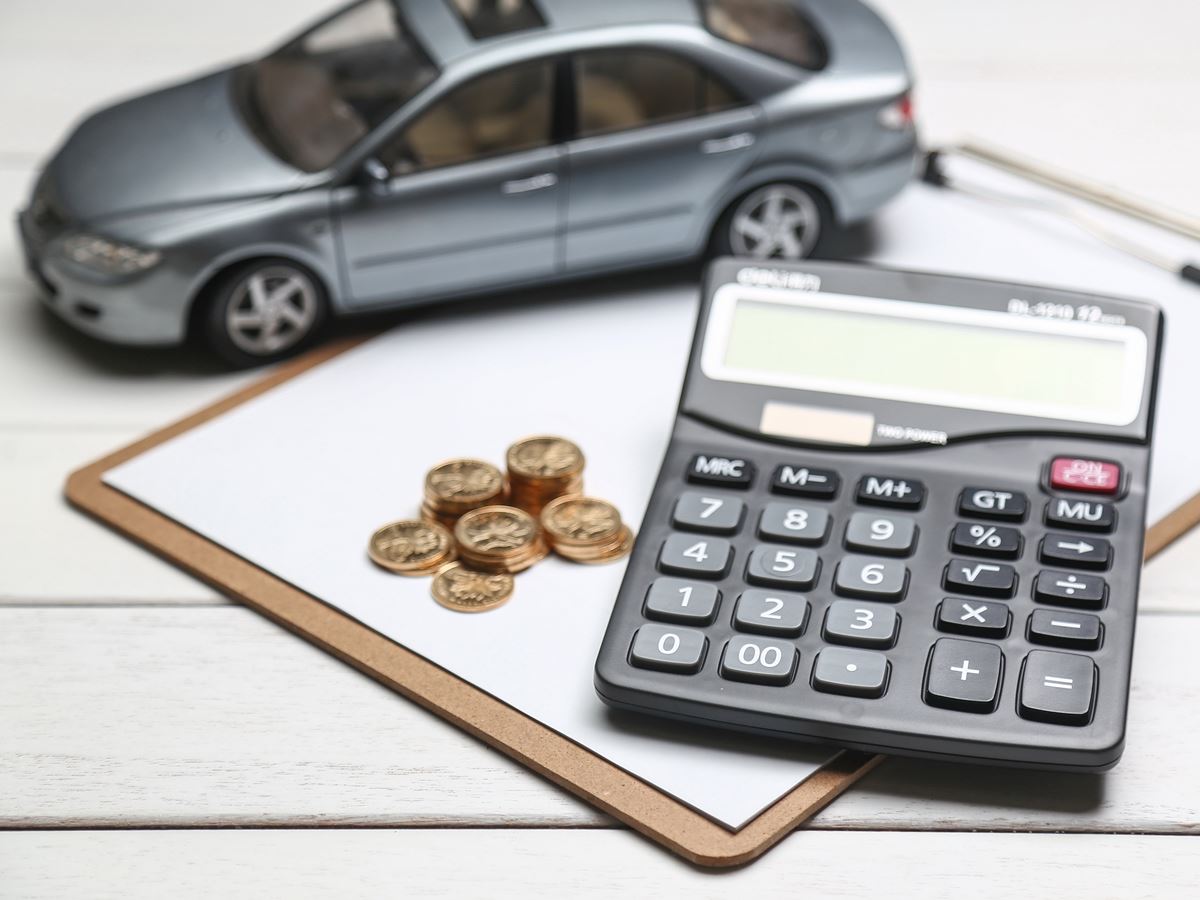 car model,calculator and coins on white table car model,calculator and coins on white table
