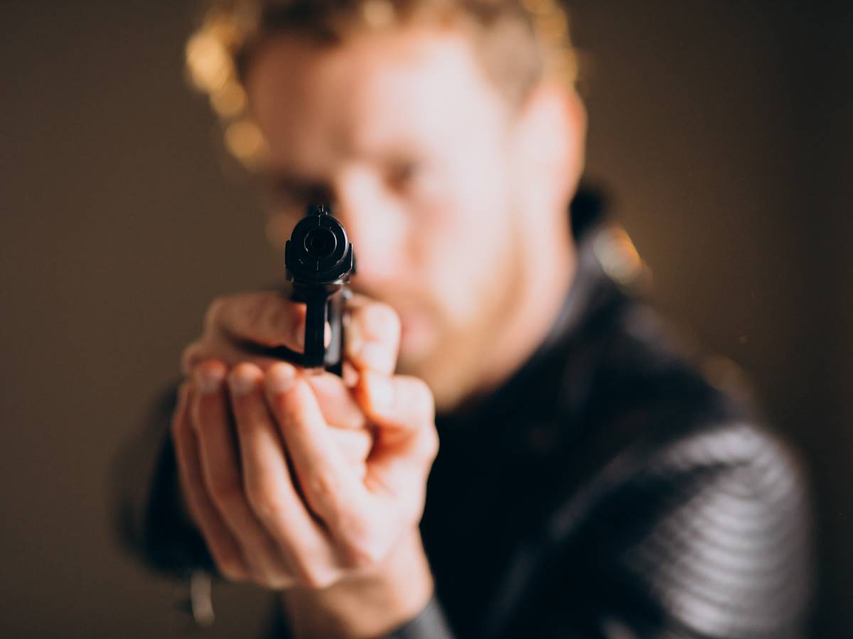 Handsome man actor posing in studio with weapon Handsome man actor posing in studio with weapon