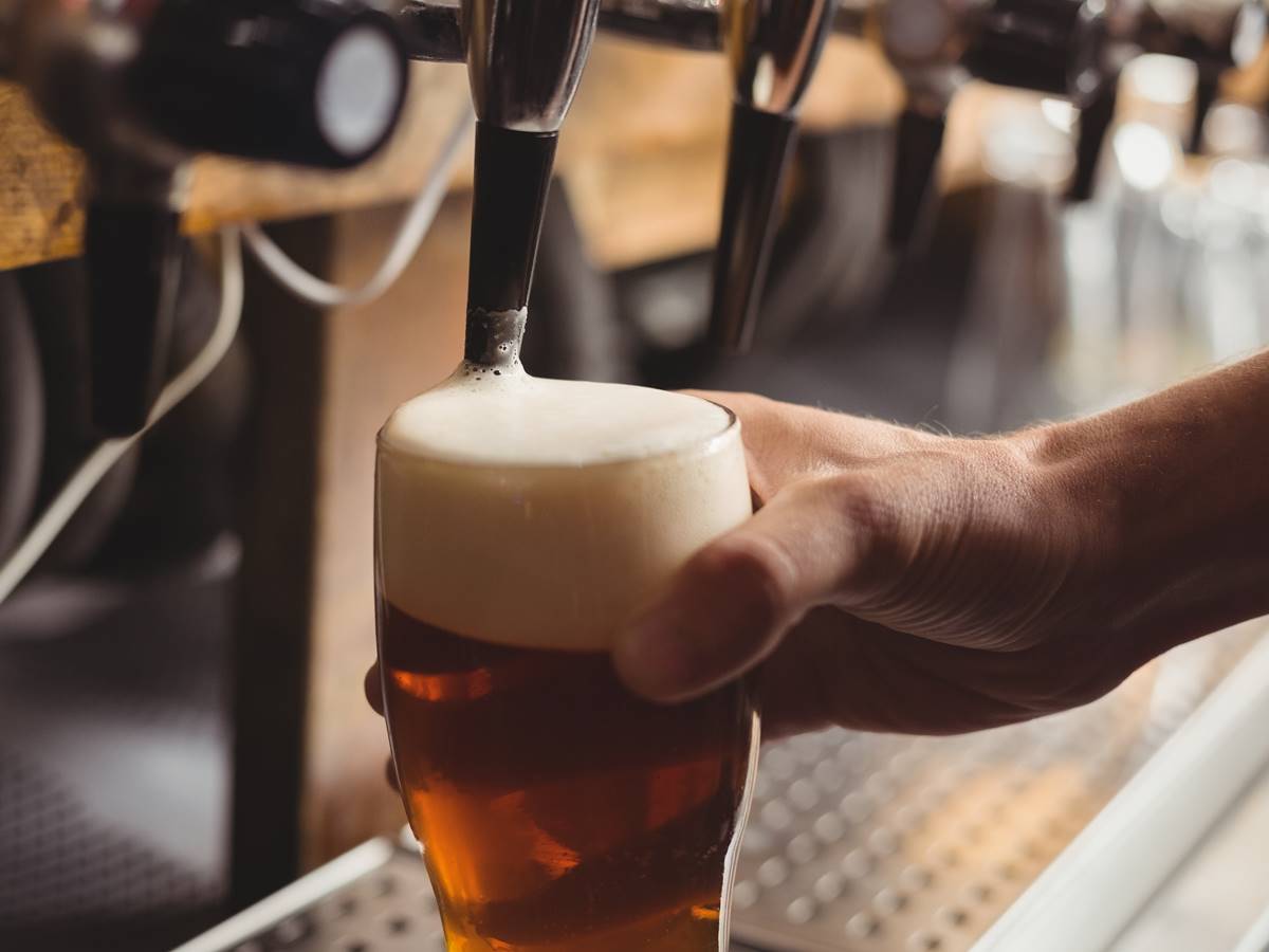 Close-up of bar tender filling beer from bar pump at bar counter Close-up of bar tender filling beer from bar pump at bar counter
