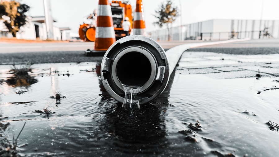 Selective closeup shot of a gray pipe with water coming out its hole A selective closeup shot of a gray pipe with water coming out its hole