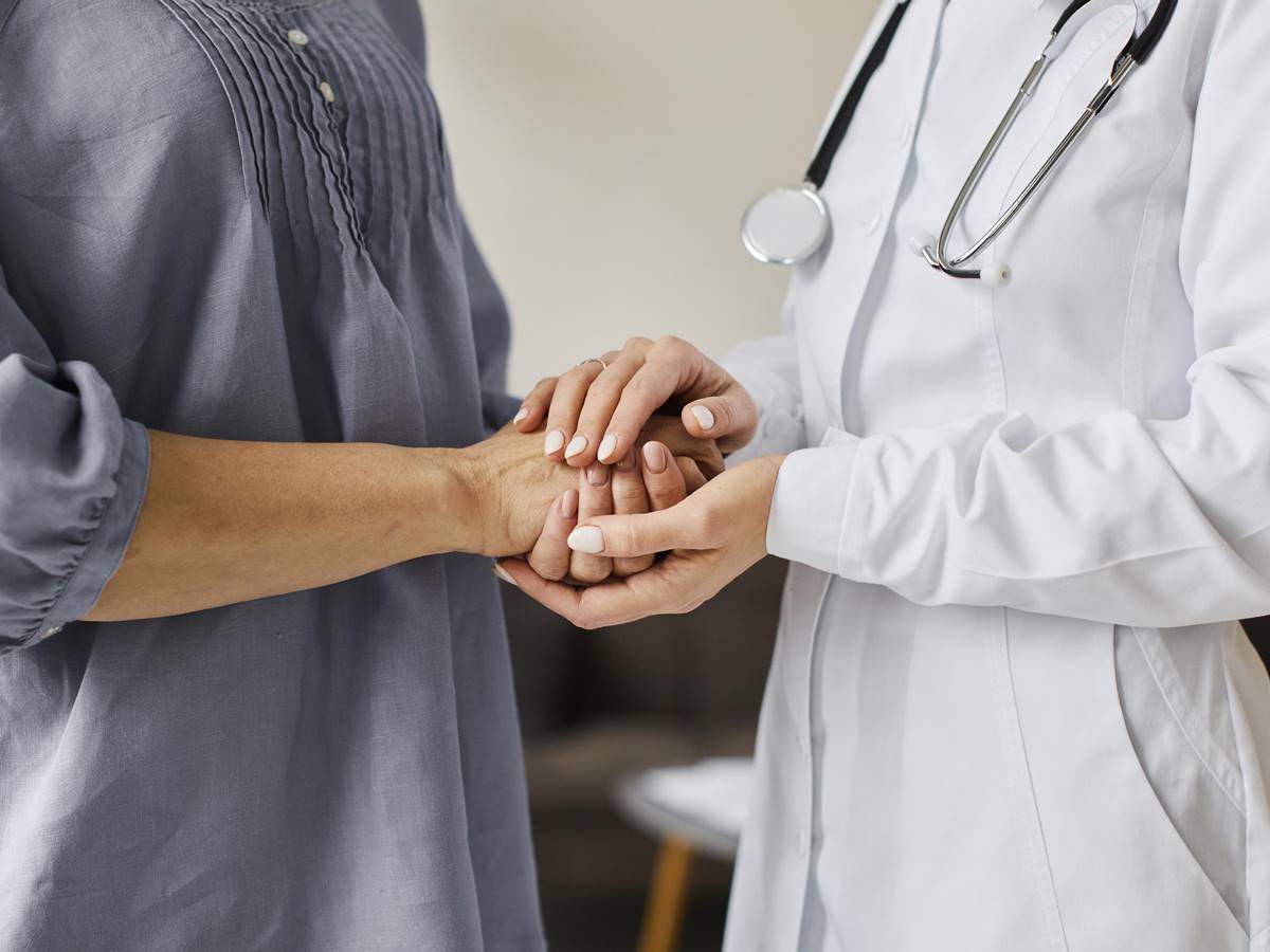 medica-do-centro-de-recuperacao-covid-segurando-as-maos-de-uma-paciente-mais-velha medica-do-centro-de-recuperacao-covid-segurando-as-maos-de-uma-paciente-mais-velha