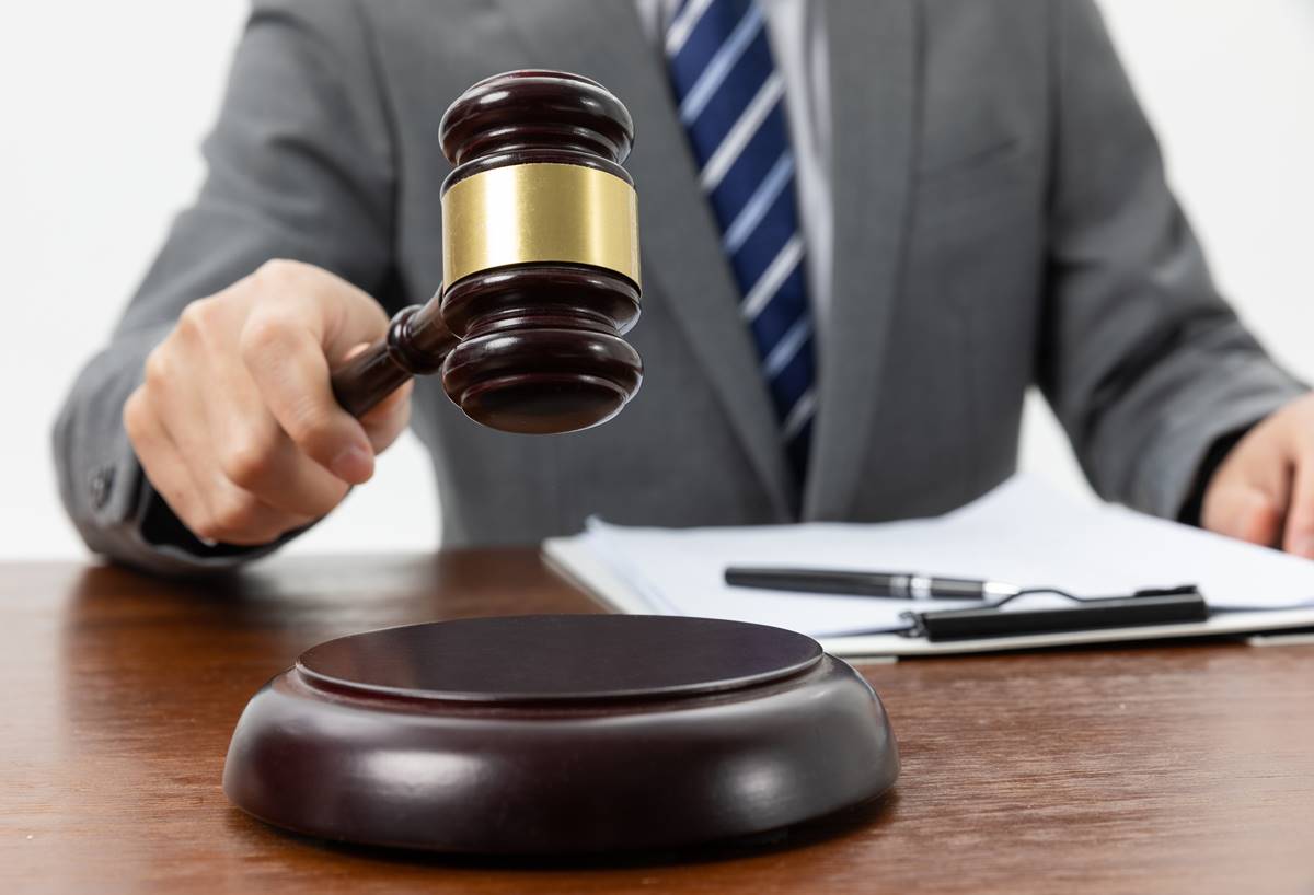Closeup shot of a person holding a gavel on the tabl A closeup shot of a person holding a gavel on the table