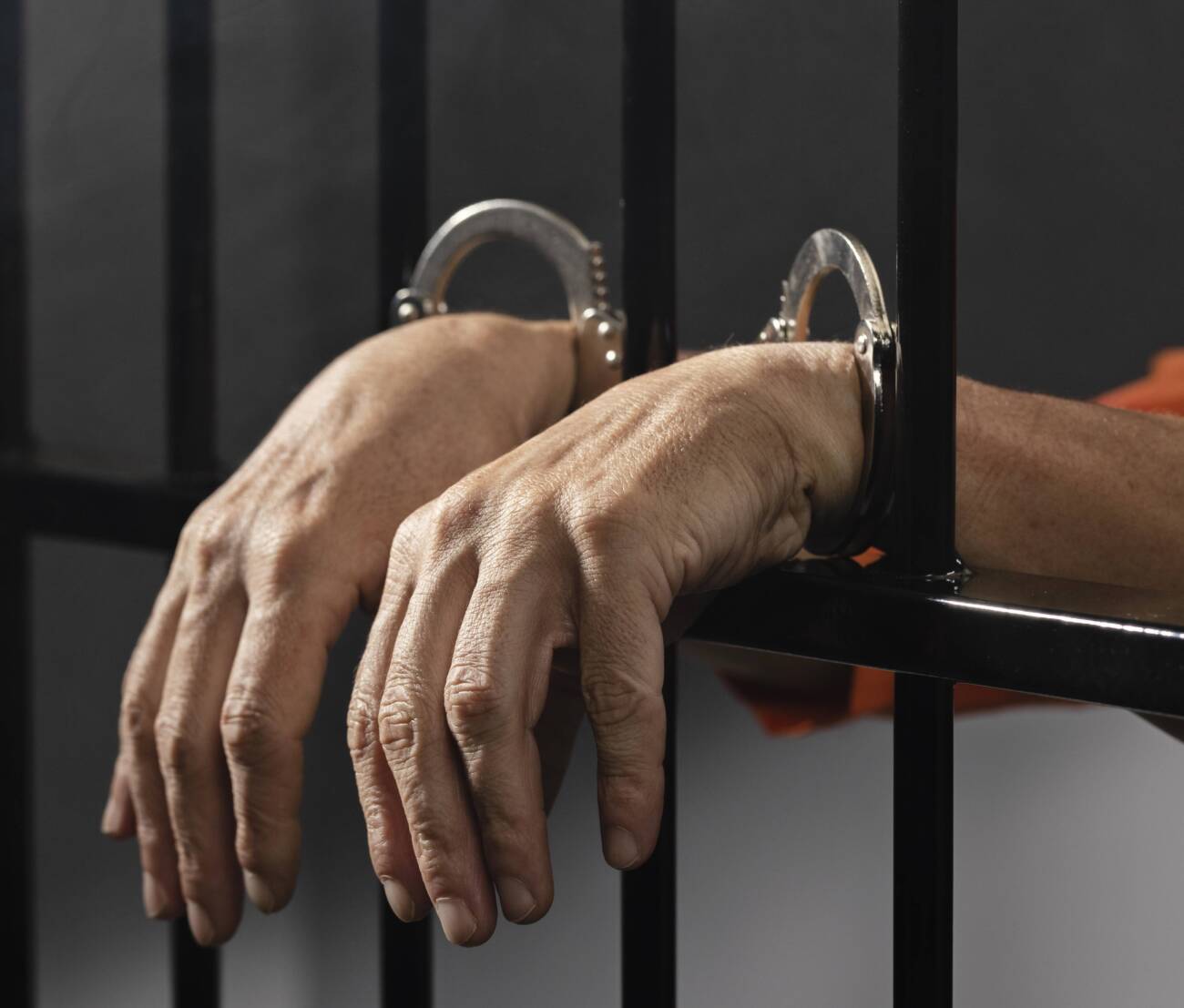 close-up-hand-wearing-cuffs-jail close-up-hand-wearing-cuffs-jail