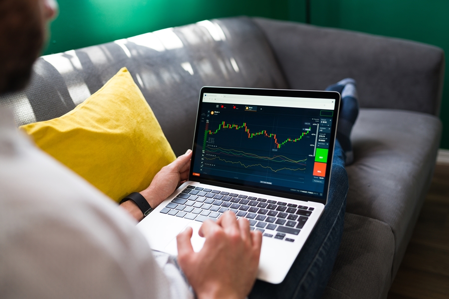 Businessman analyzing and investing Trading finances. Young man resting on the couch while checking the stock market on the laptop