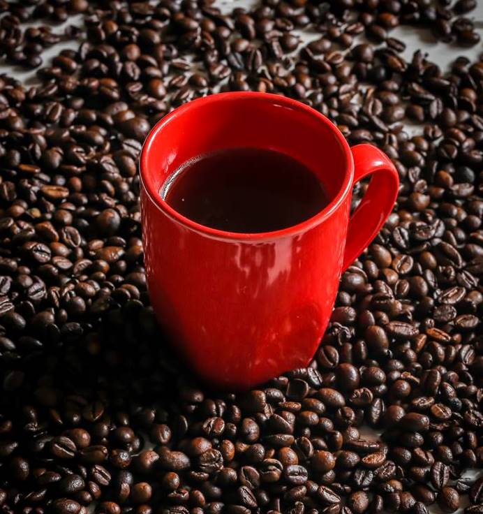 red Cup with coffee beans red Cup with coffee beans on wooden background