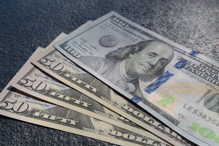 Closeup shot of three fifty and one hundred dollars bills on a gray background A closeup shot of three fifty and one hundred dollars bills on a gray background