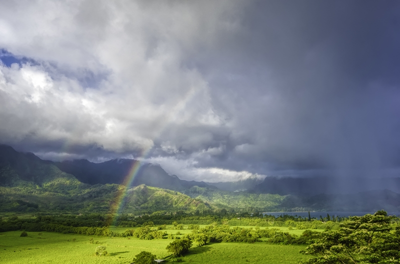 Beautiful landscape with green grass and the breathtaking view of the rainbow in the storm clouds A beautiful landscape with green grass and the breathtaking view of the rainbow in the storm clouds