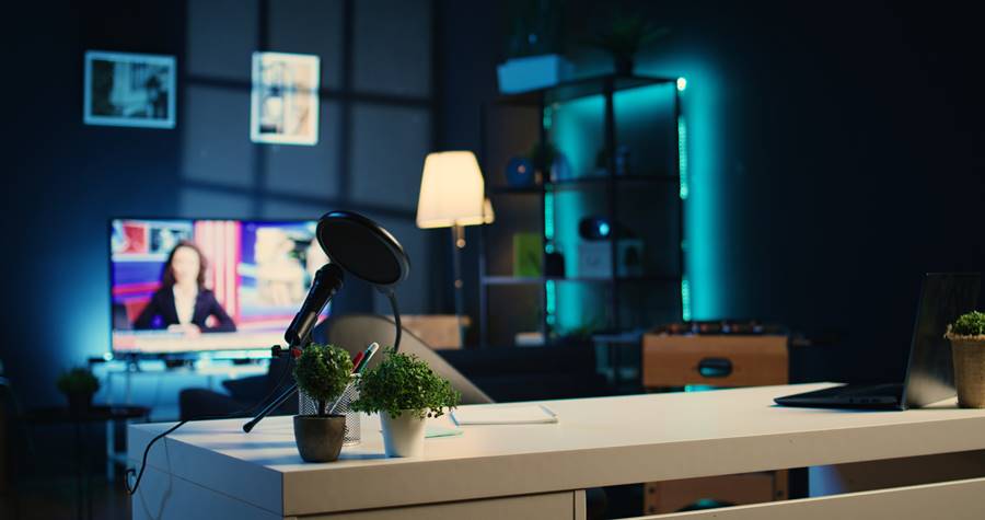 Empty home studio used in internet show Empty home studio interior illuminated with neon lights at night, used for internet show production. Apartment filled with content creation equipment, TV running in background, handheld camera shot