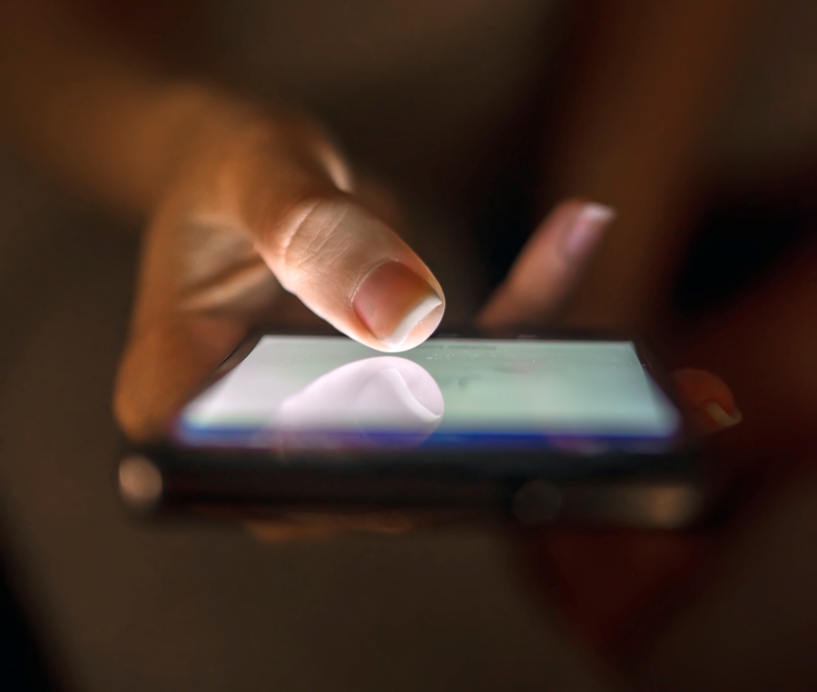 Close up of businesswoman using smart phone with blank screen at home at night