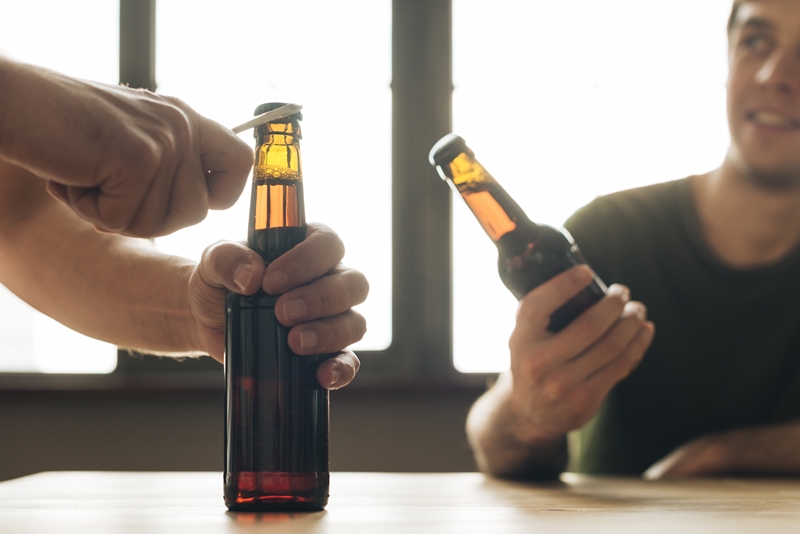 man-looking-person-opening-brown-beer-bottle-restaurant (1)