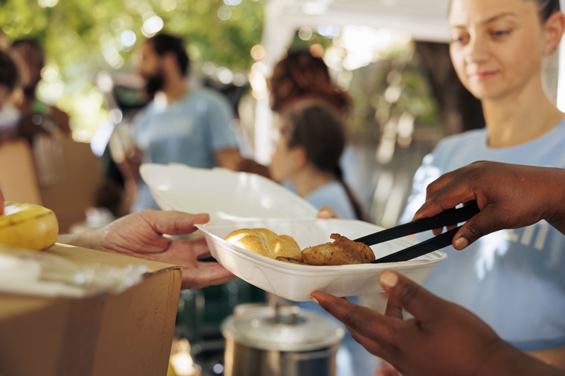 Volunteers handing out meal boxes to help the poor and less fortunate, embodying compassion and humanitarian aid. Image captures the spirit of food drive, offering free food to homeless individuals.