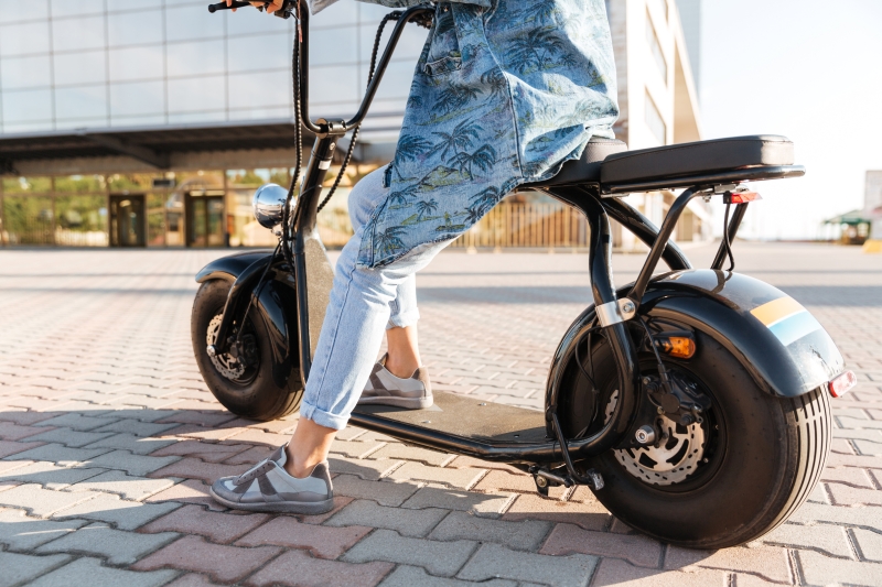 Cropped image of a woman sitting on a motor bicycle outdoors