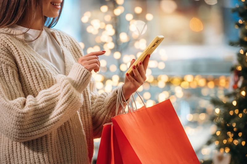Red shopping bags. New year presents. Woman is near the Christmas tree.