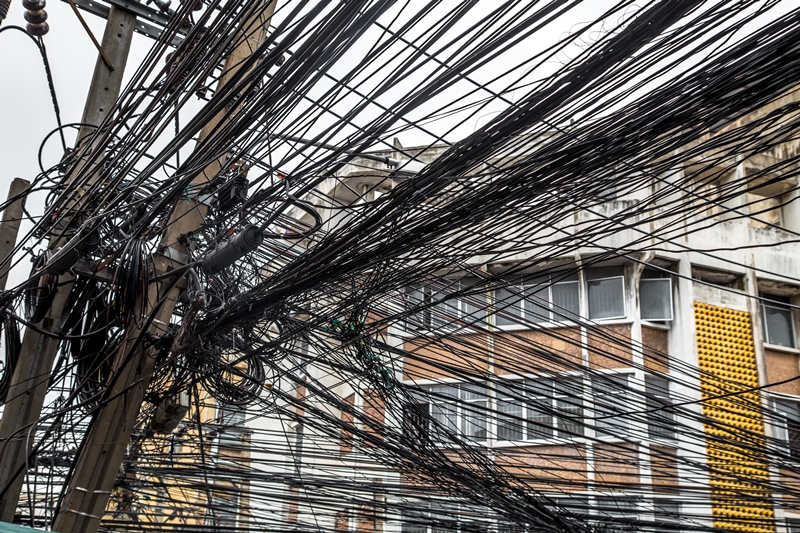 Messy wires attached to the electric pole, the chaos of cables and wires on an electric pole in Bangkok, Thailand, concept of electricity