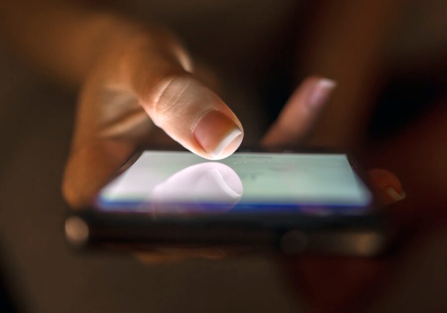 Close up of businesswoman using smart phone with blank screen at home at night