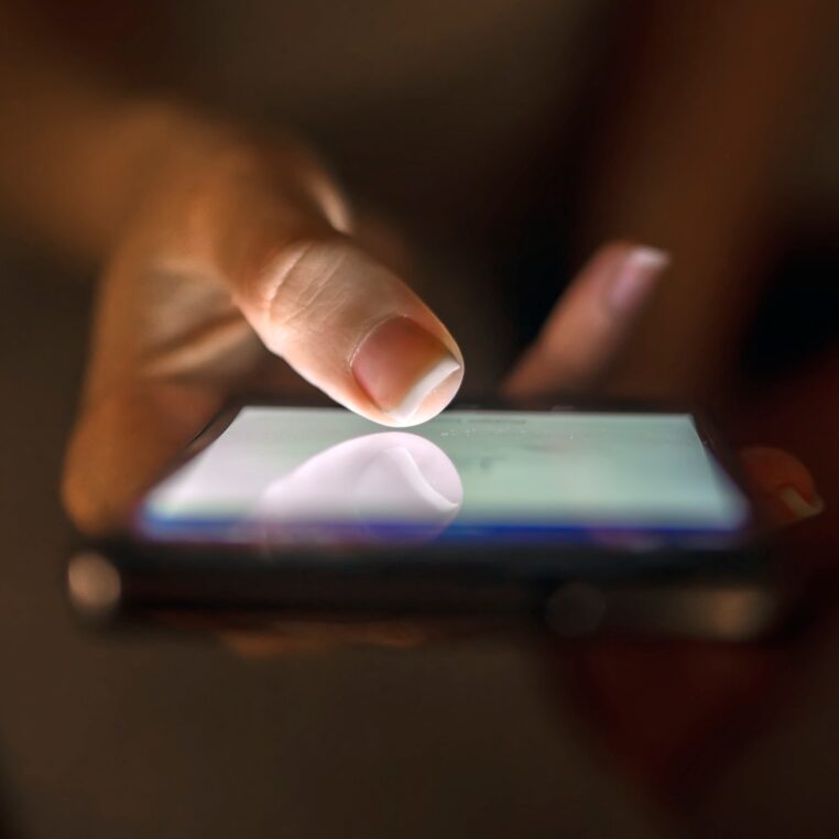 Close up of businesswoman using smart phone with blank screen at home at night