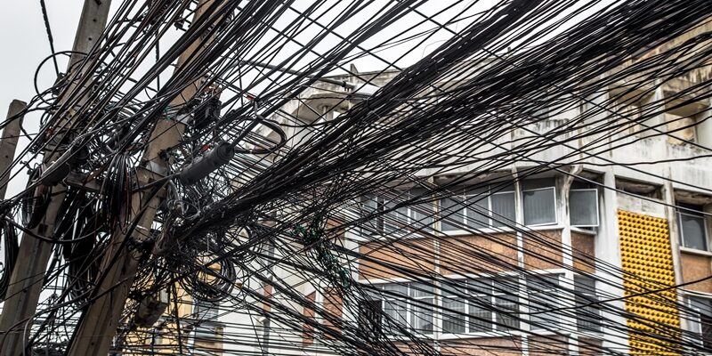 Messy wires attached to the electric pole, the chaos of cables and wires on an electric pole in Bangkok, Thailand, concept of electricity