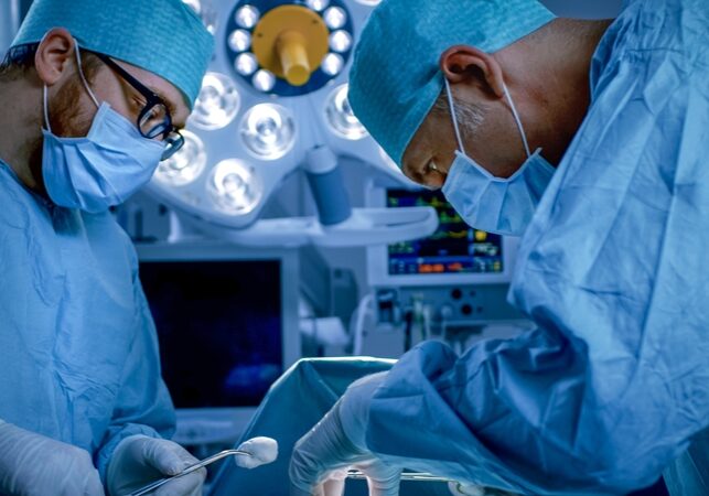 In the Hospital Operating Room Diverse Team of Professional Surgeons and Nurses Suture Wound after Successful Surgery.