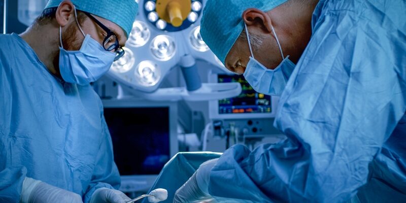 In the Hospital Operating Room Diverse Team of Professional Surgeons and Nurses Suture Wound after Successful Surgery.