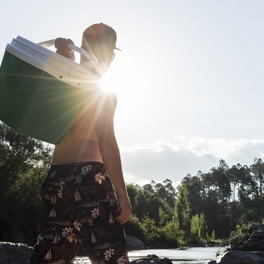 male-with-cool-box-sand-coast-near-river