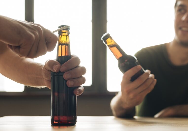 man-looking-person-opening-brown-beer-bottle-restaurant (1)